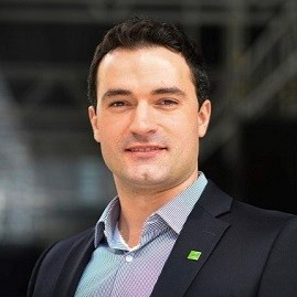 A man in a blazer and button-up shirt smiles at the camera. 