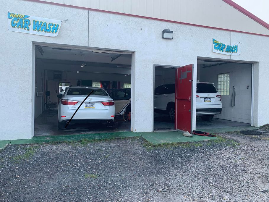 A white car wash with three bays, two occupied by vehicles. The building has a white exterior and 