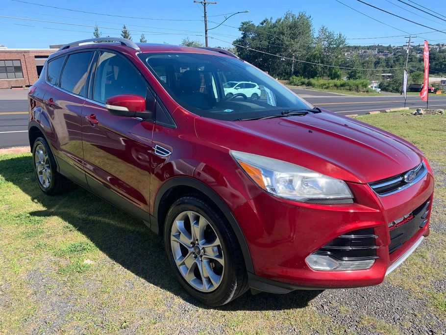 Red Ford Escape SUV parked on grass in front of a building on a sunny day.