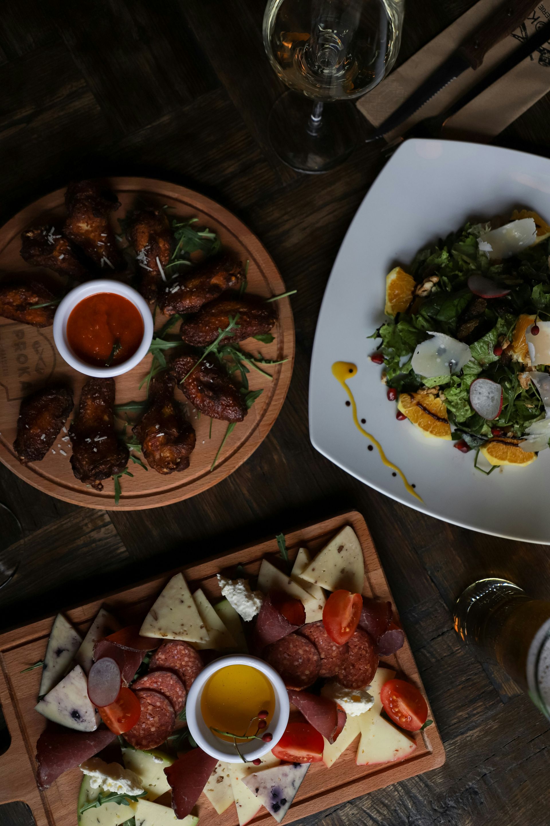 A table topped with plates of food and a glass of wine.