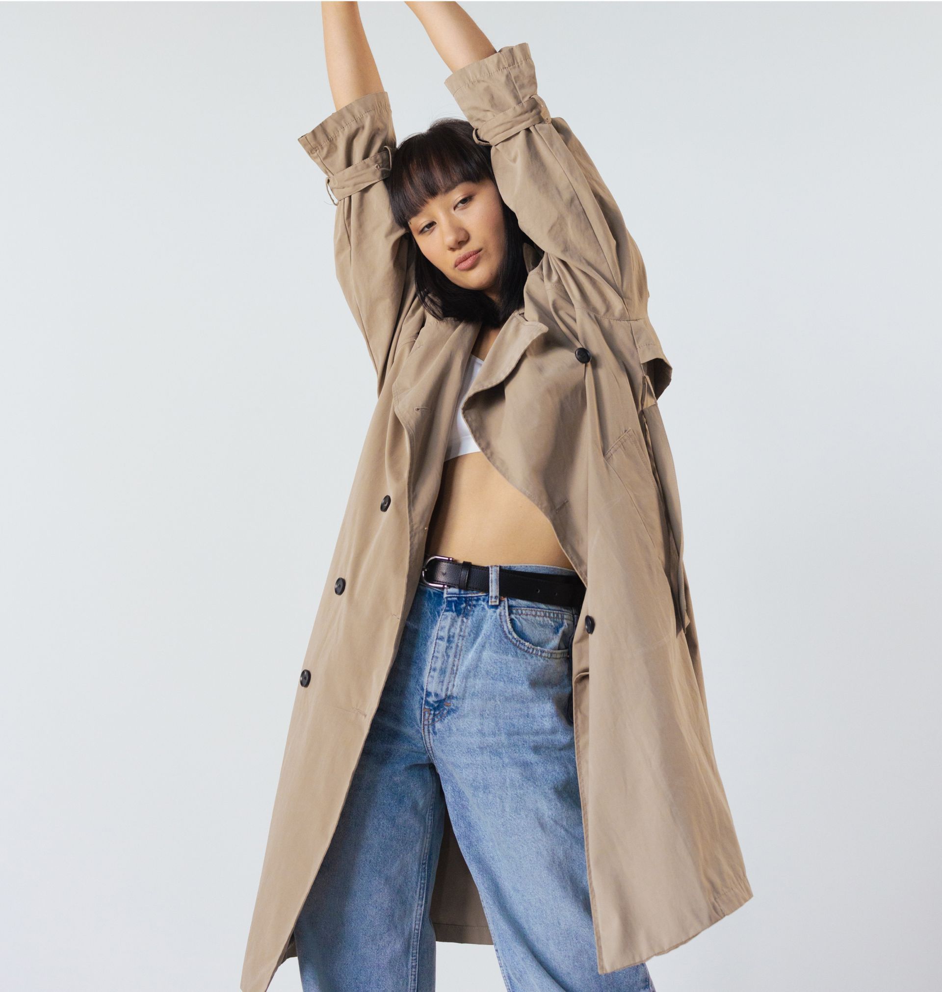 A woman is wearing a trench coat and jeans