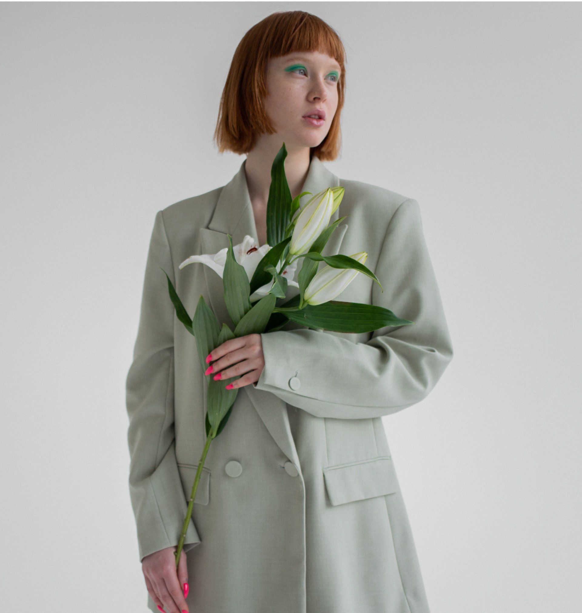 A woman in a green jacket is holding a bouquet of flowers.