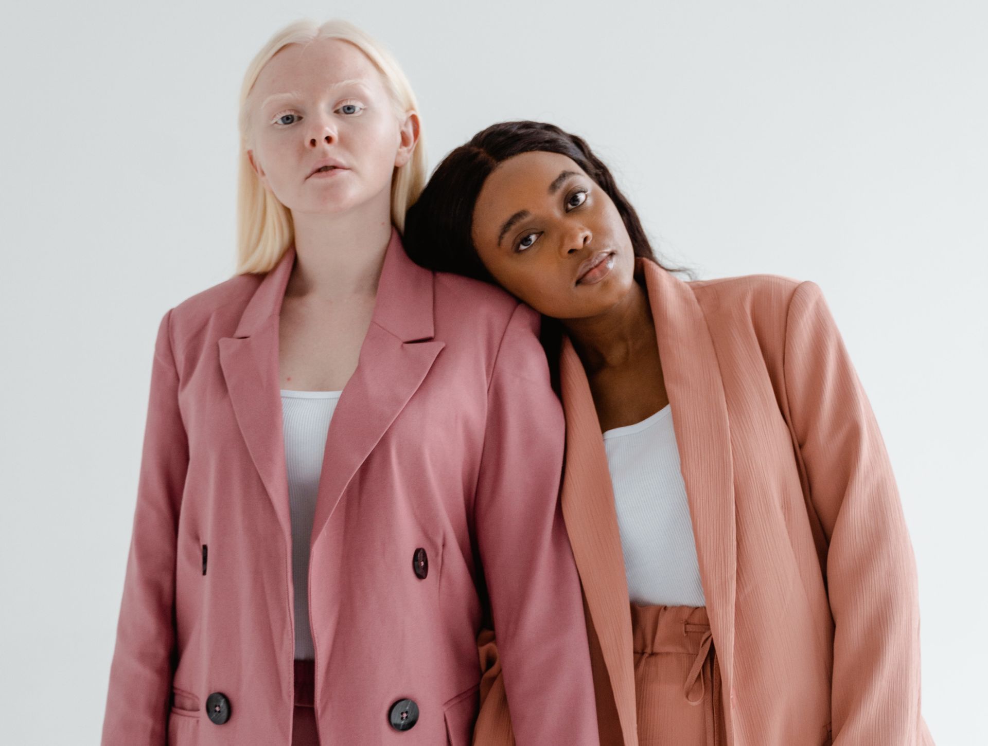 Two women in pink suits are standing next to each other.