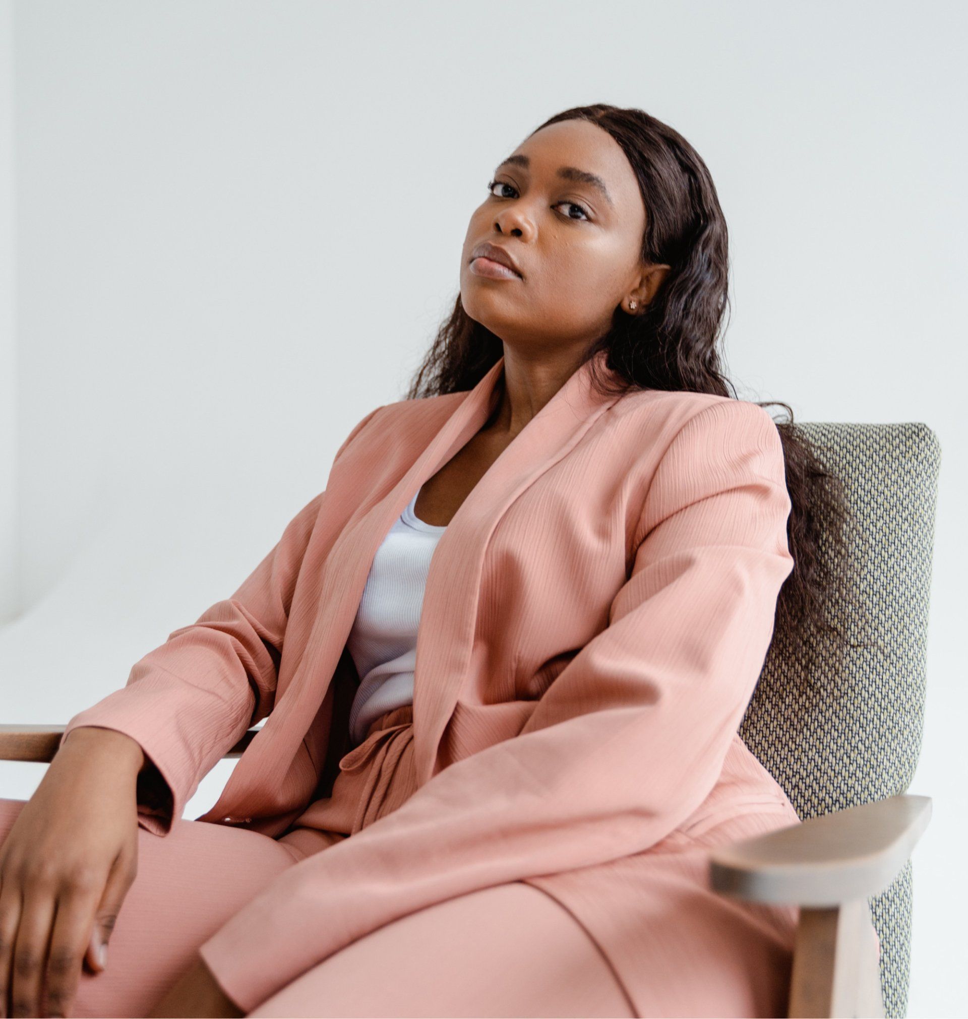 A woman in a pink suit is sitting in a chair.