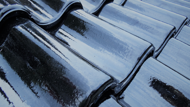 Black, glossy ceramic roof tiles, curved shape, reflecting light.