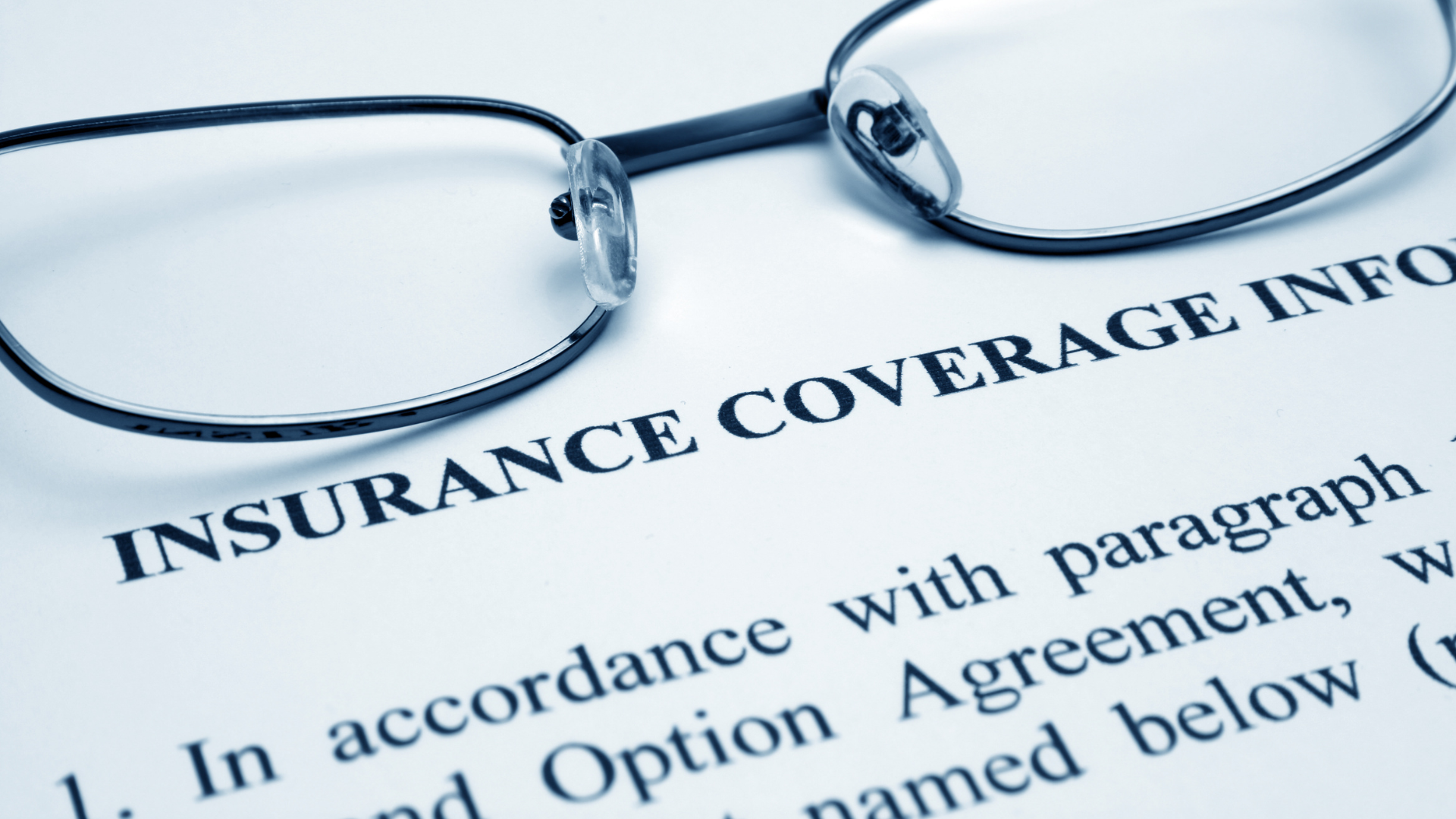 Eyeglasses on insurance coverage document.