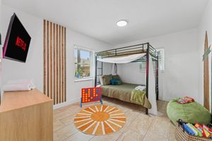 Bedroom with bunk bed, TV, wooden accents, and orange rug.
