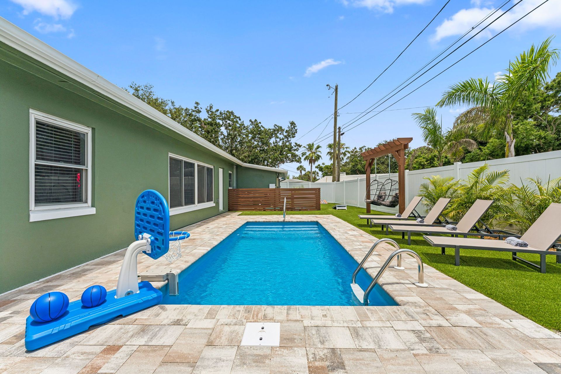 Woman in straw hat smiles, holding wine glass near a lake.