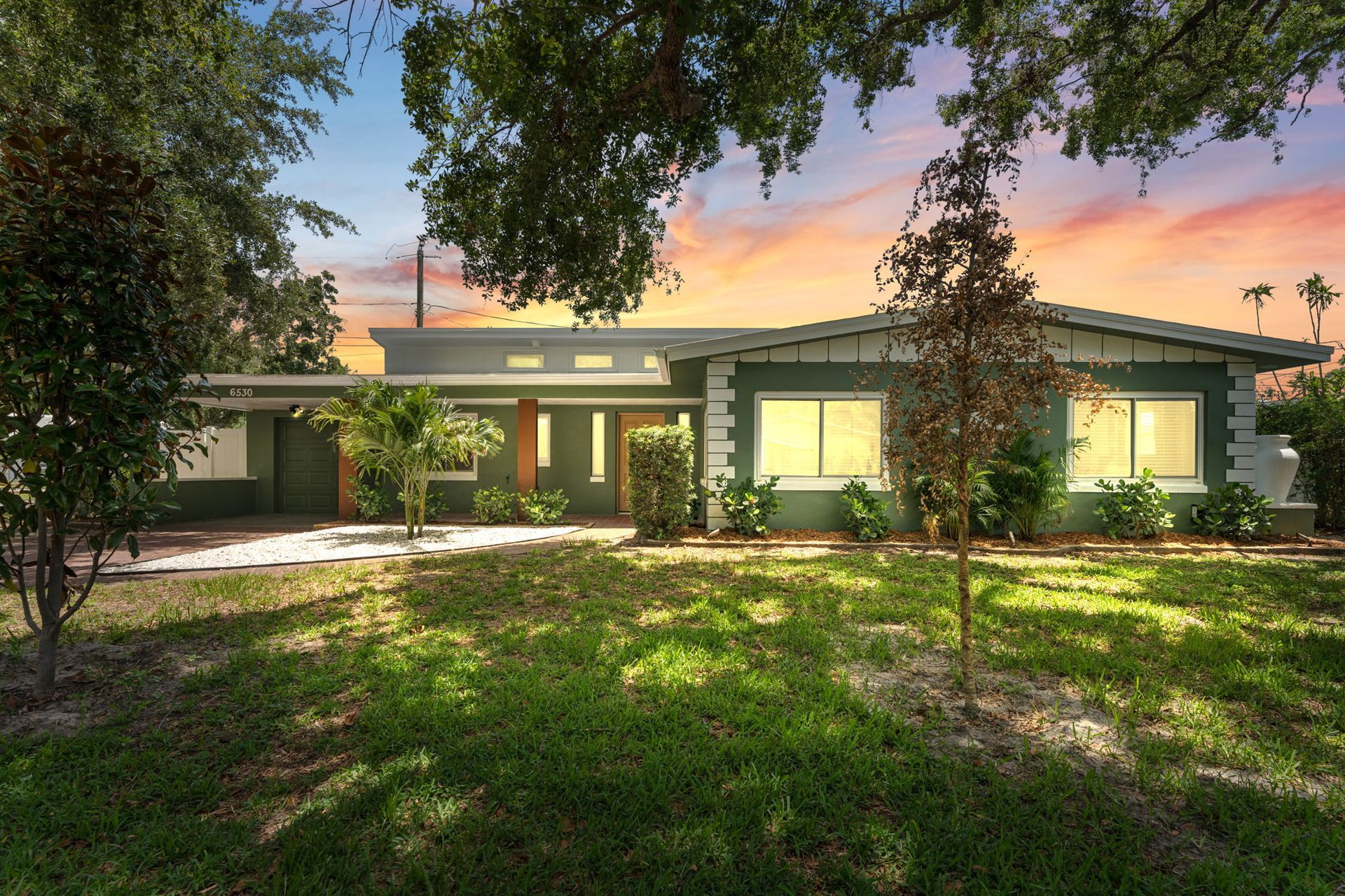 A person holding a baby up in the air indoors near a window, baby smiling.