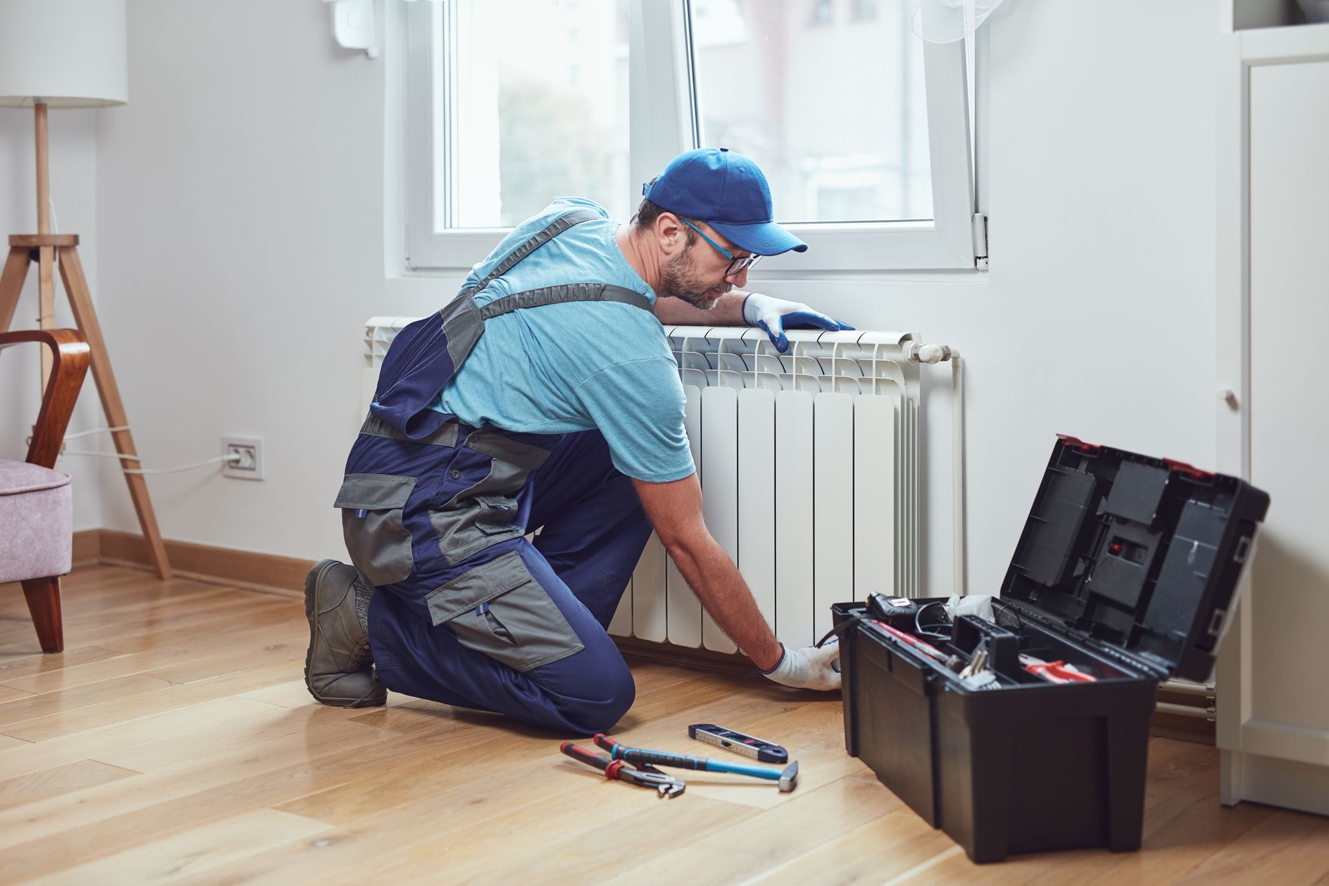 Woman in straw hat smiles, holding wine glass near a lake.