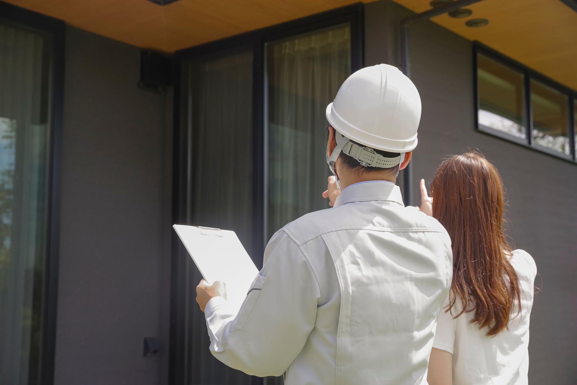 Woman in straw hat smiles, holding wine glass near a lake.