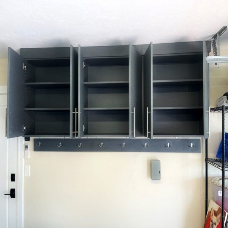 Open dark gray wall cabinets above a row of hooks in a small laundry or utility room