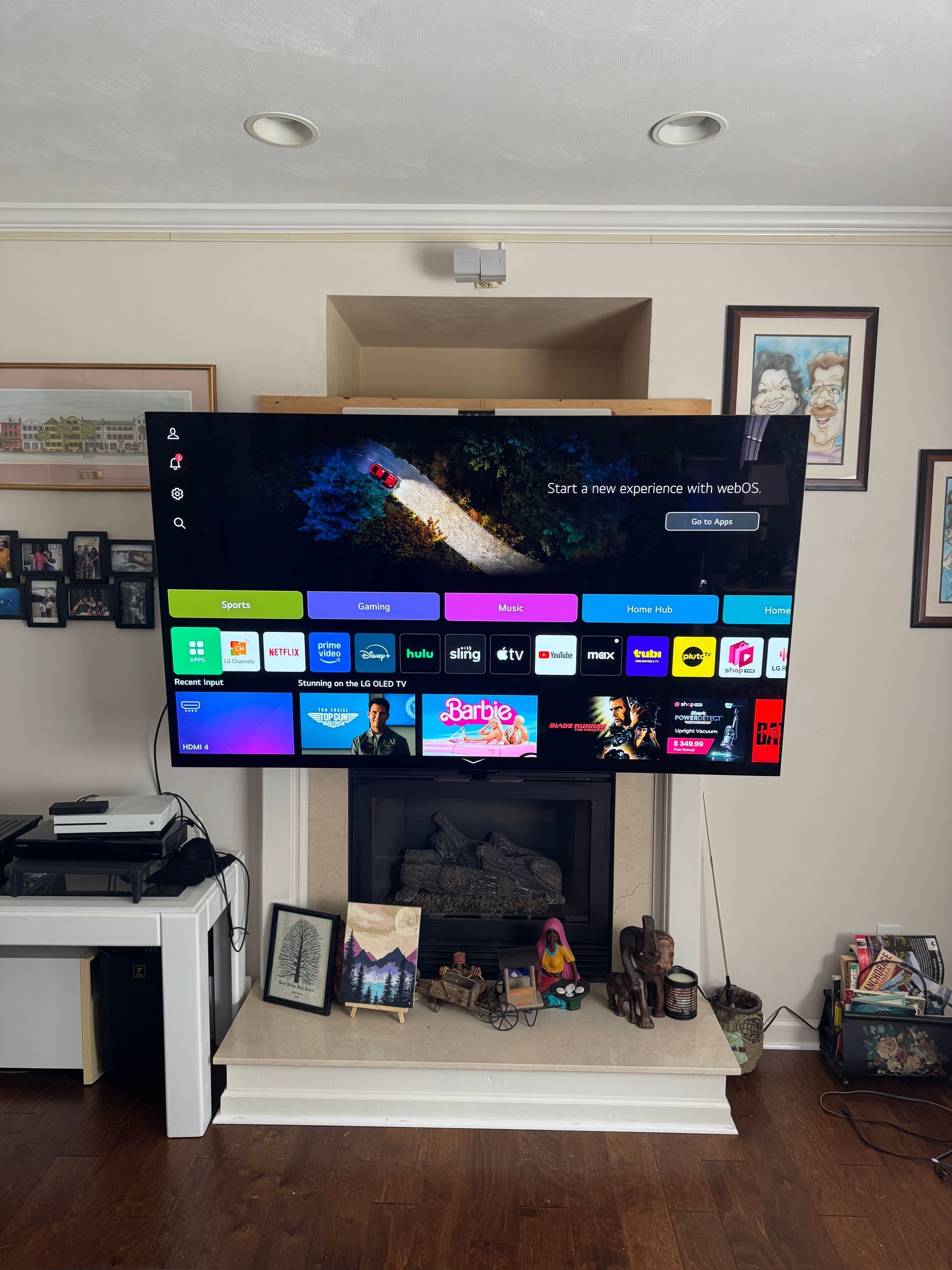 Living room with a large TV on a stand displaying a streaming home screen and photos arranged below it