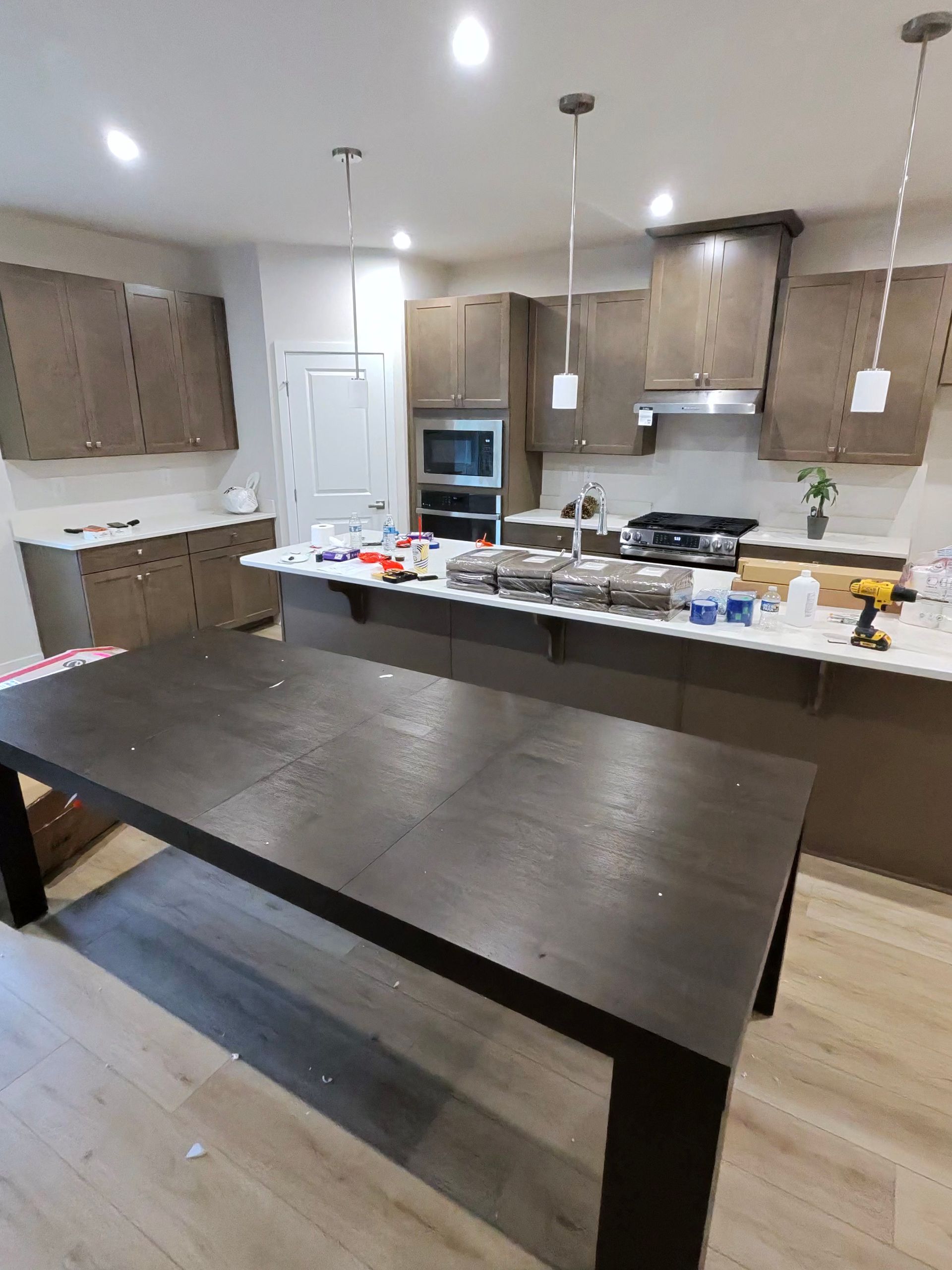 Modern kitchen with dark island, wood cabinets, stainless appliances, and a cluttered countertop