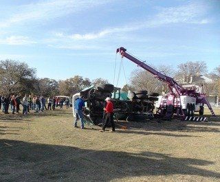 Towing company providing major truck wrecker service for tipped vehicle on the side of the road in Winters, TX