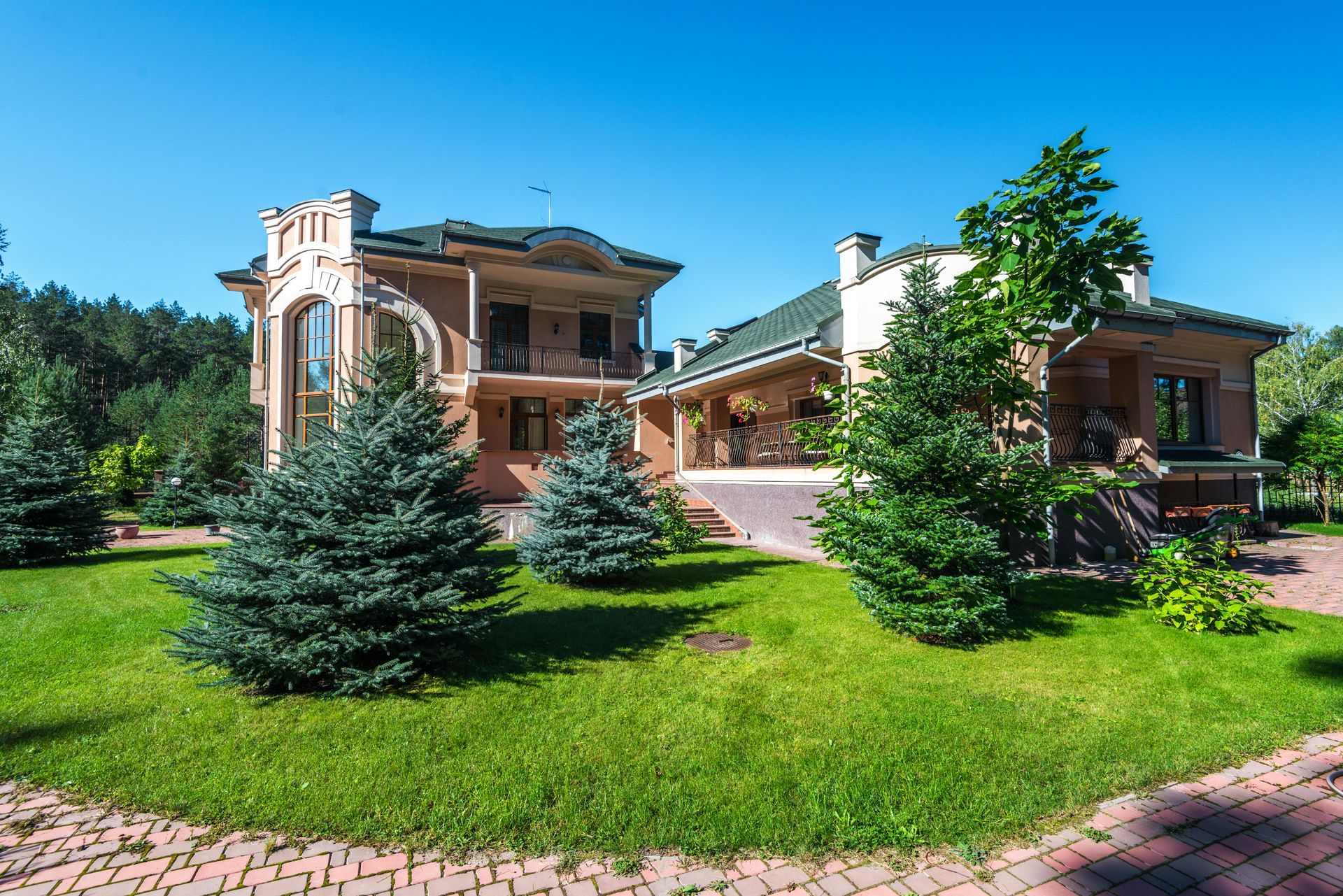 A large house with a lush green lawn and trees in front of it.