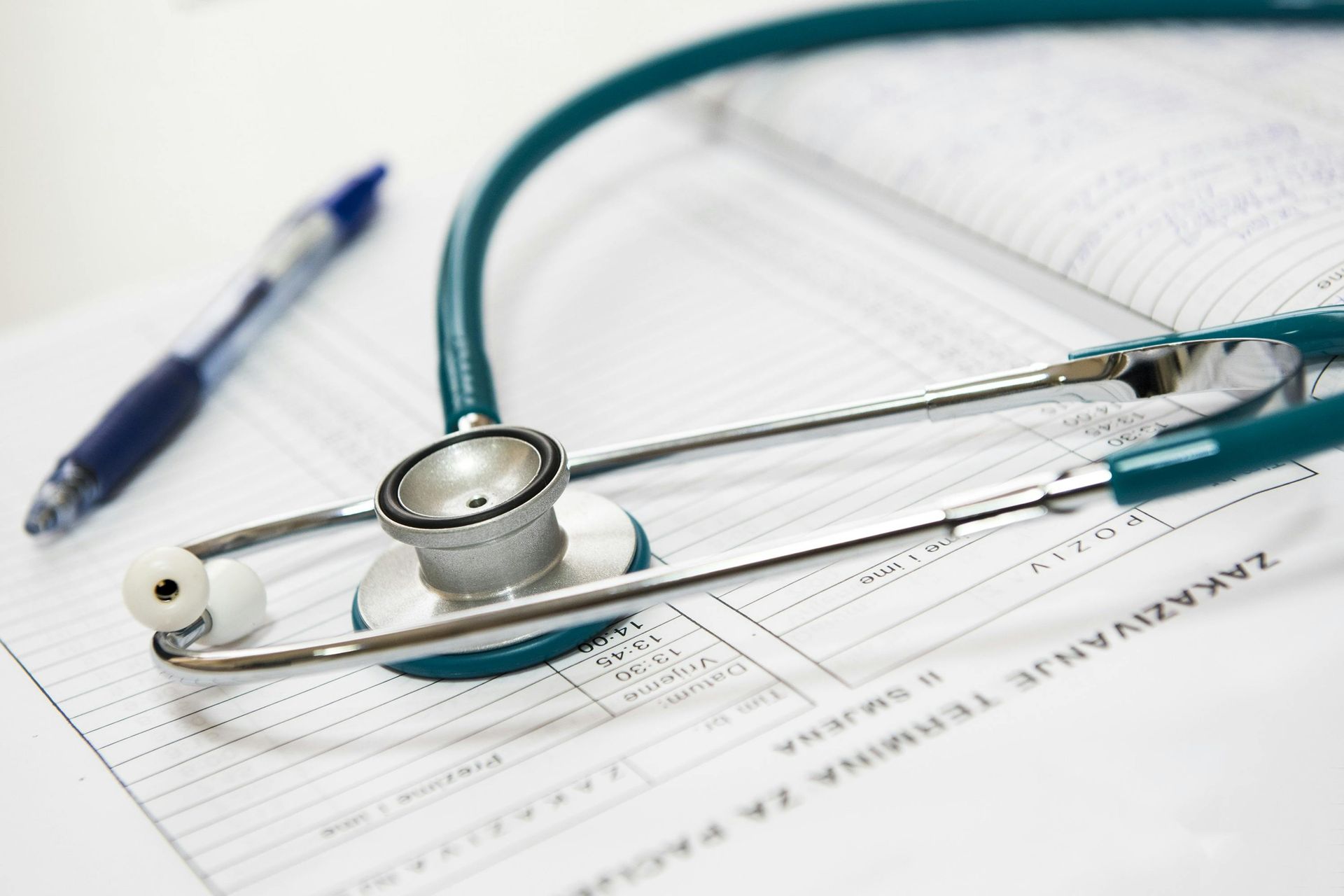 Stethoscope on medical forms with a pen, indicating a healthcare setting.