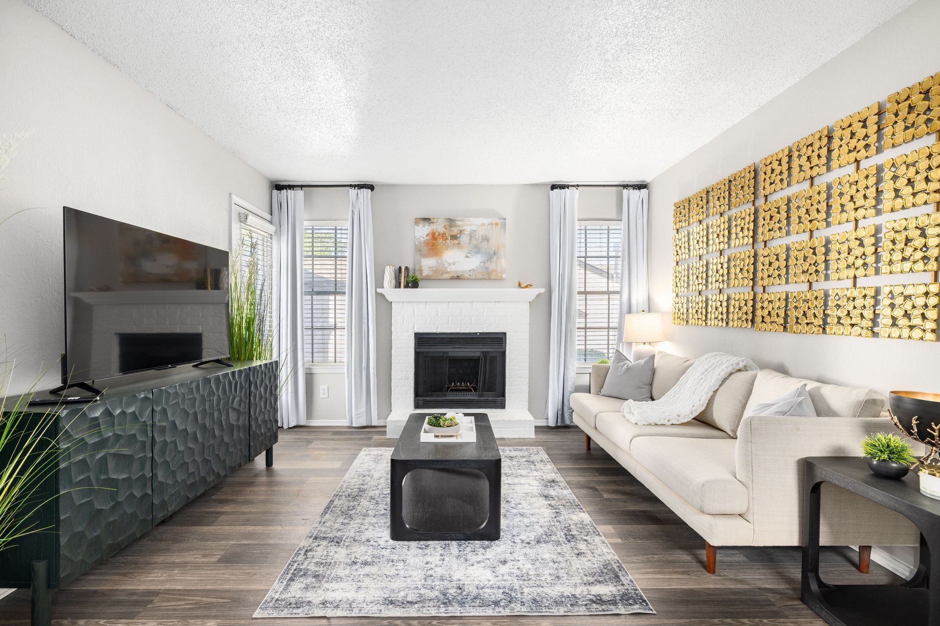An empty living room with hardwood floors and sliding glass doors leading to a kitchen.