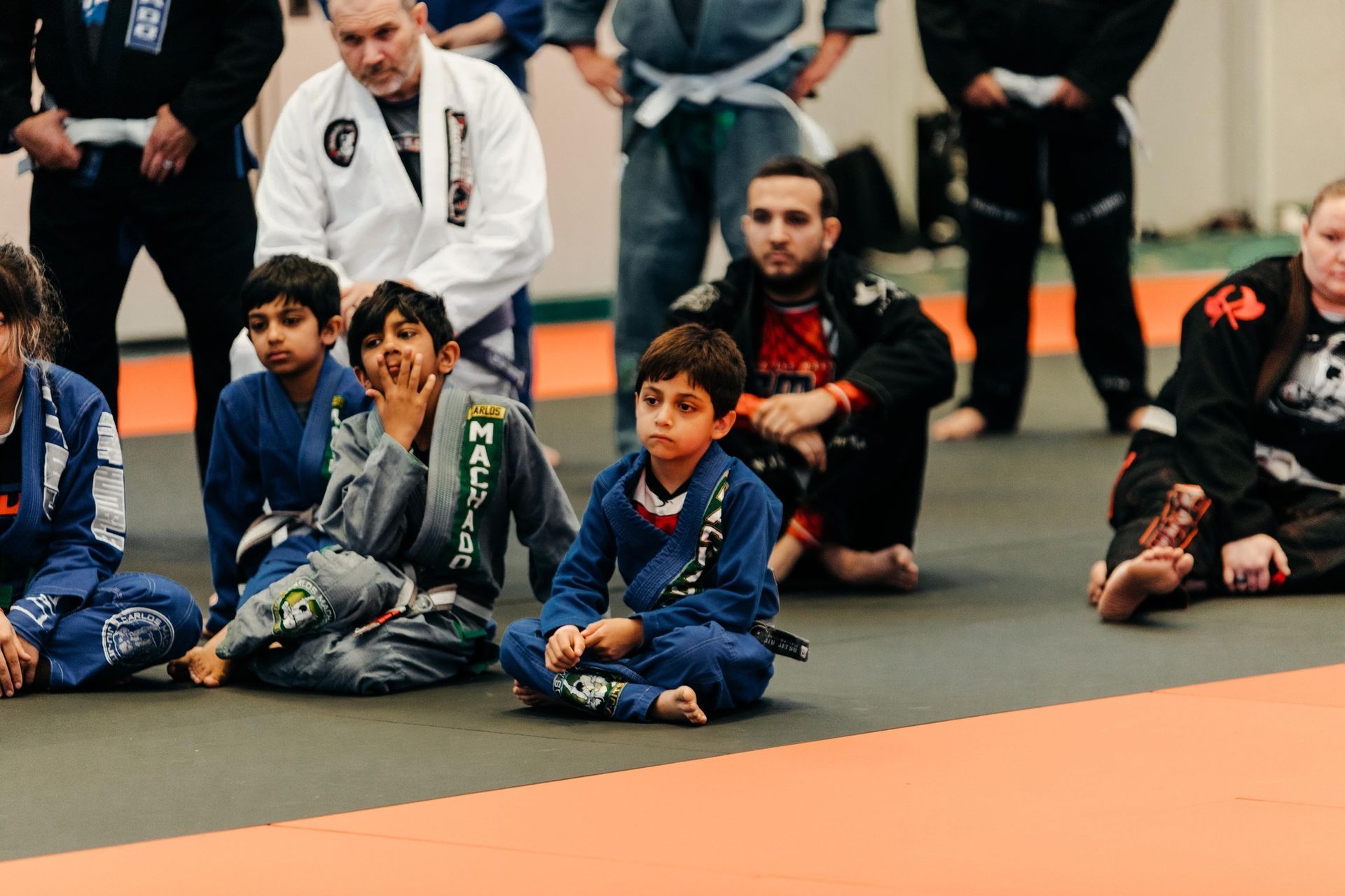 Two young boys in karate uniforms are standing next to each other in a dark room.