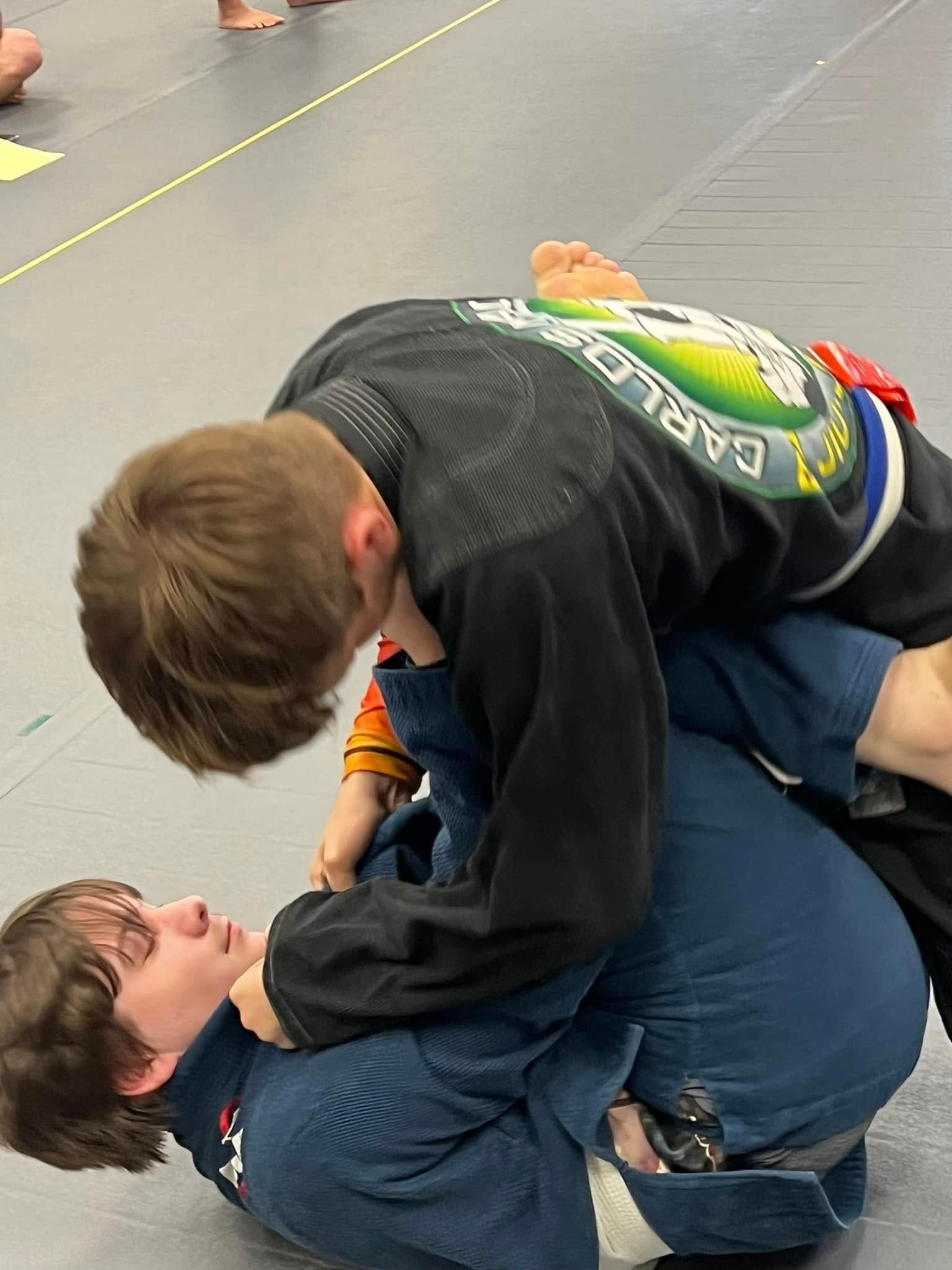 a person with a yellow belt is laying on another person 's back