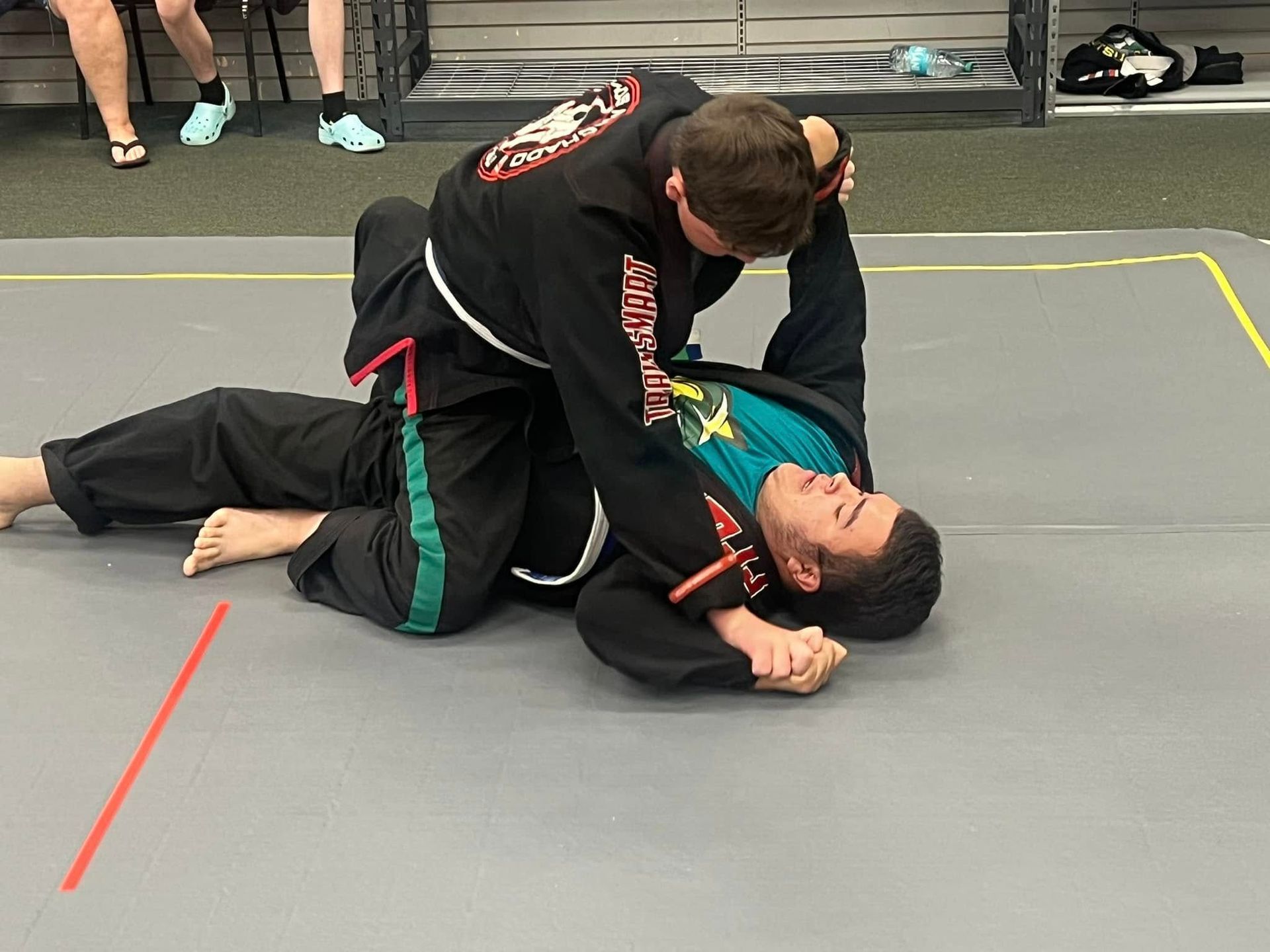 a man and a woman are wrestling on a mat in a gym .