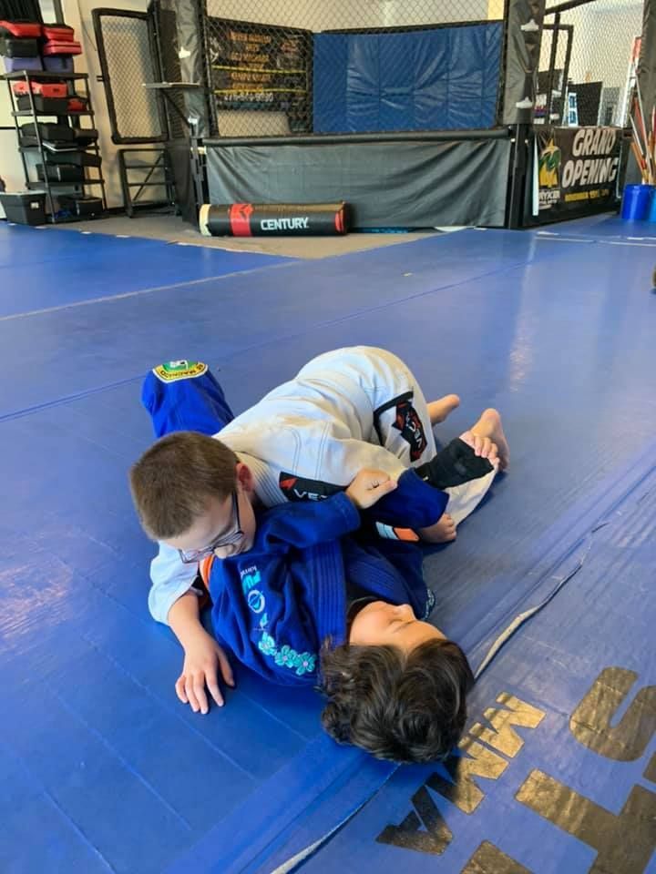 Two young boys are practicing judo in a dark room.