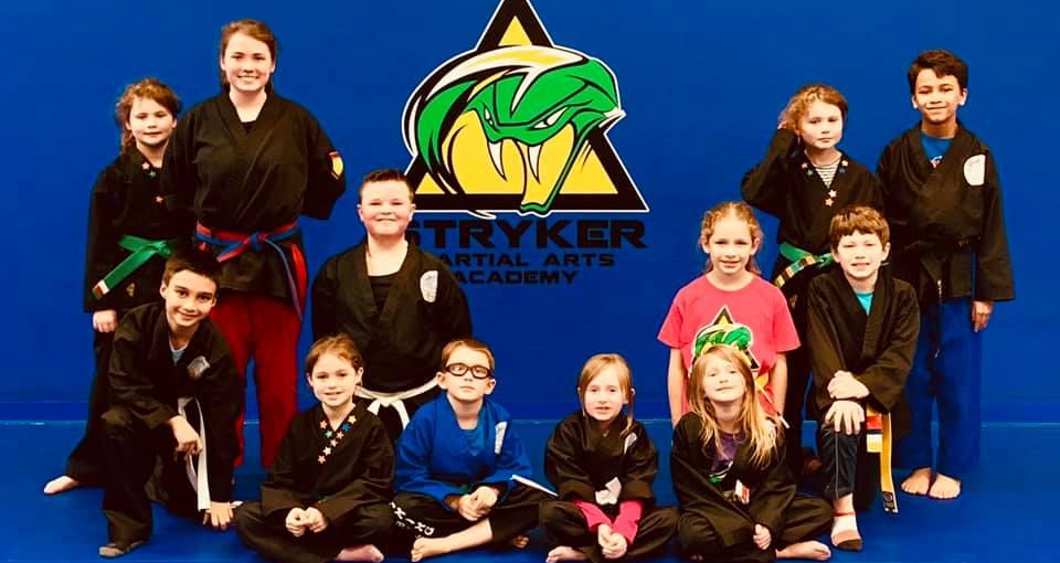 A group of young girls are practicing karate in a gym.