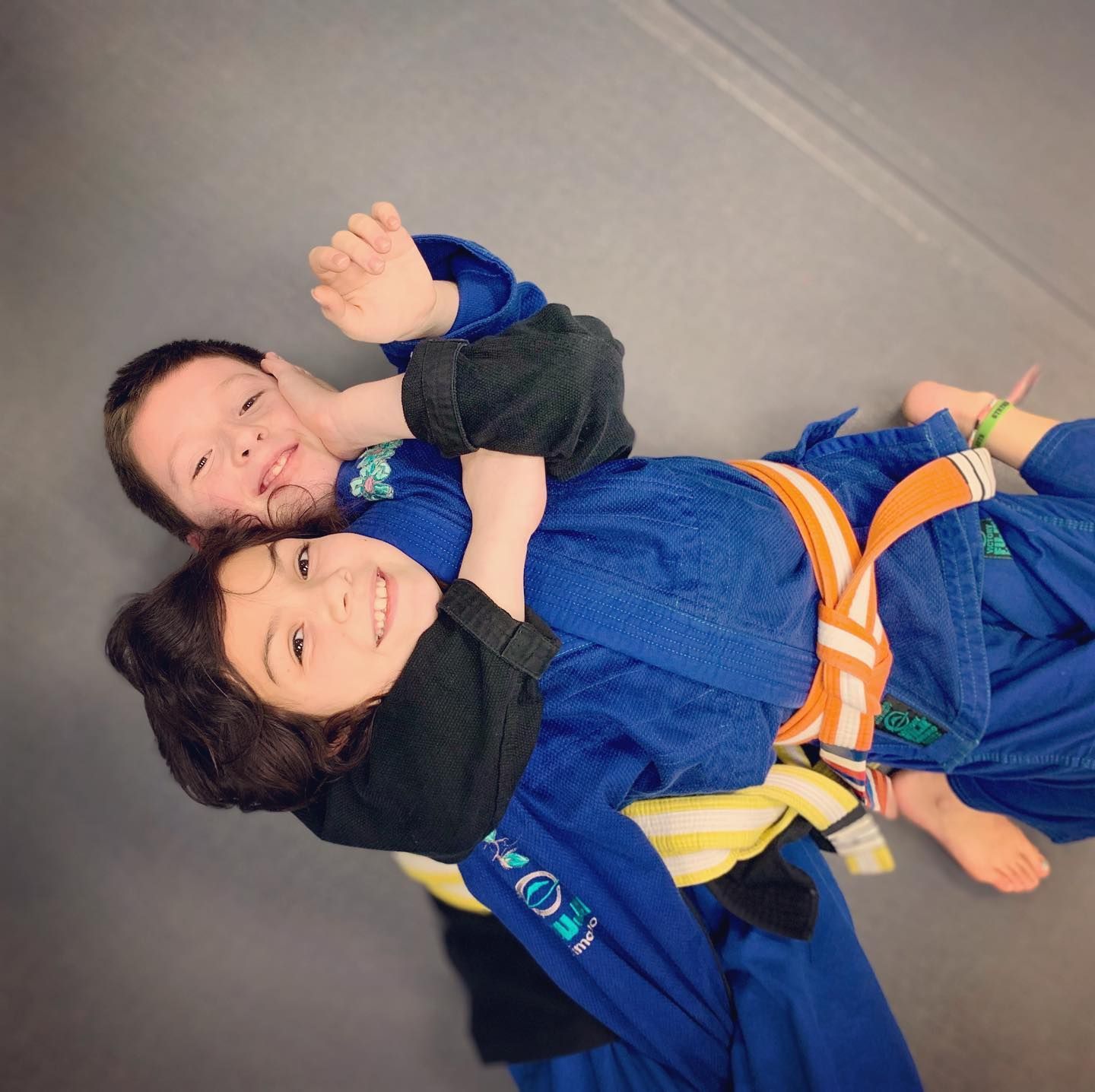 Two boys are wrestling on a mat in a gym.