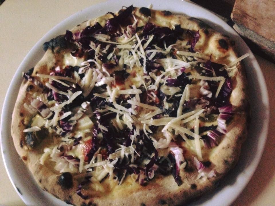 Una pizza con cavolo rosso e formaggio su un piatto bianco