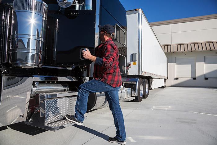 Driver stepping up into cab of truck at warehouse