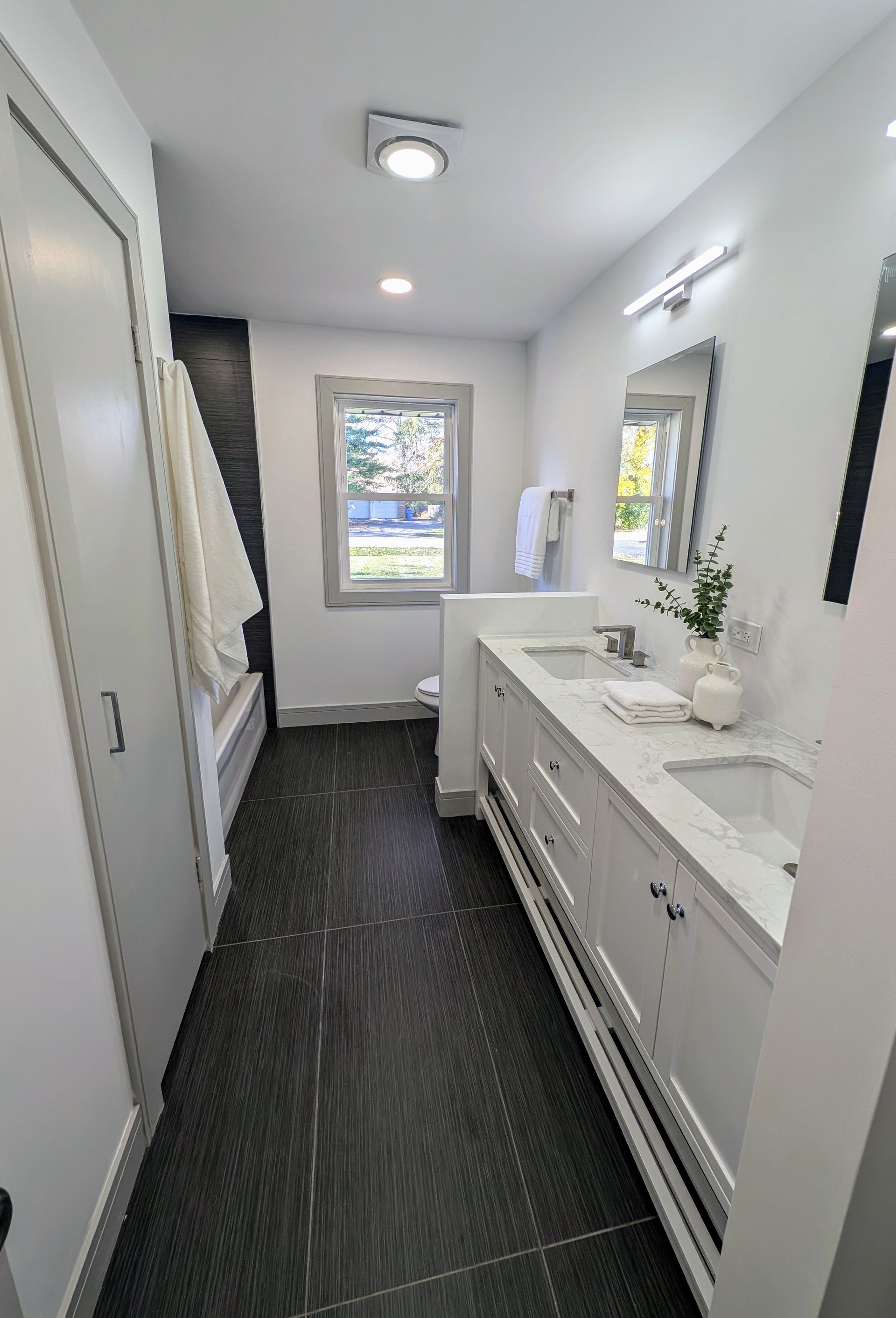 A bathroom with two sinks , a mirror and a window.