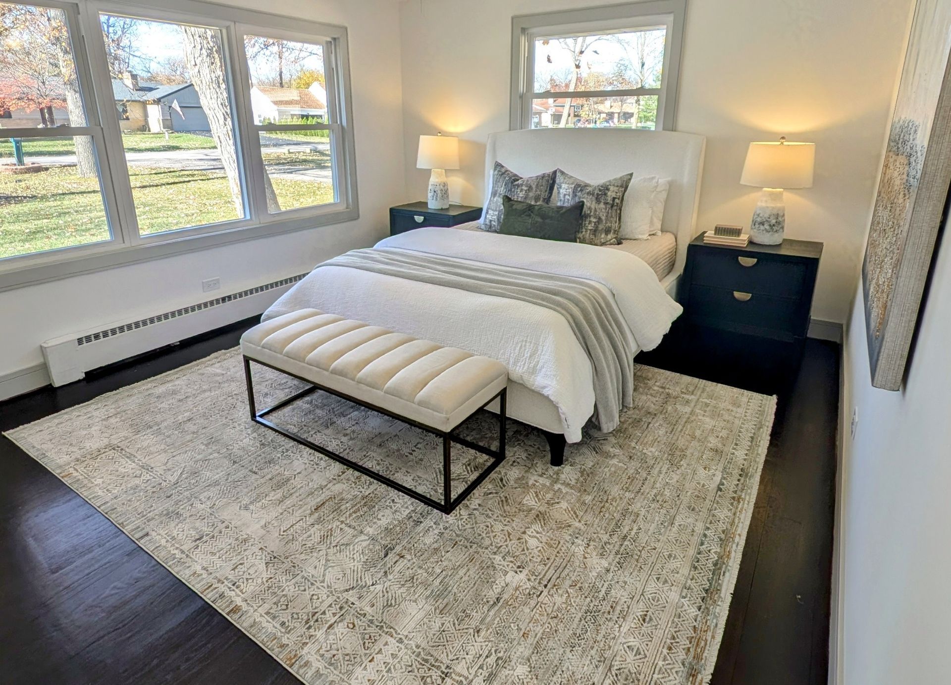 A bedroom with a bed , nightstands , a rug and a ceiling fan.