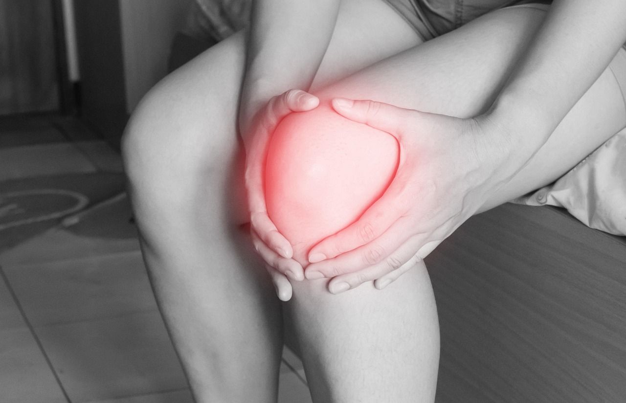 Hands holding a red throbbing Knee joint.