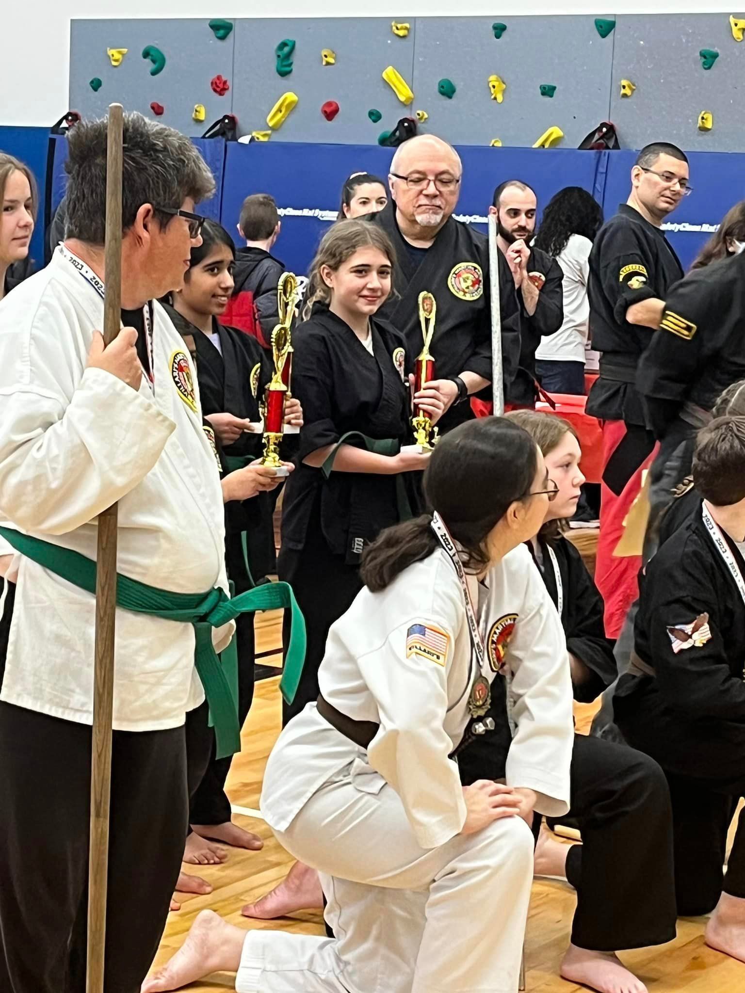 a group of people in martial arts uniforms holding trophies