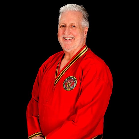 a man in a red karate uniform is smiling for the camera .