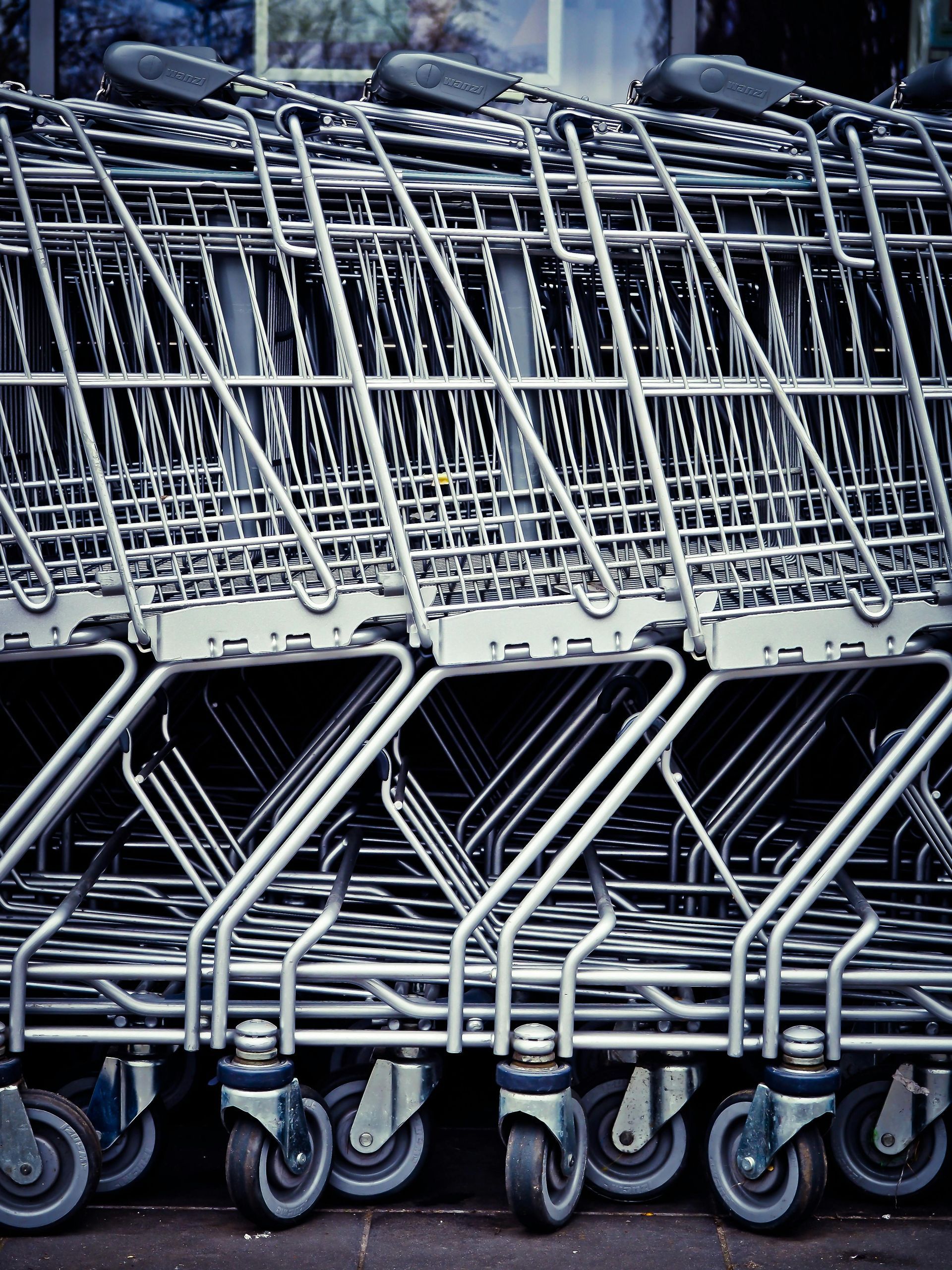 Stacked shopping carts with metal frames and rolling wheels.