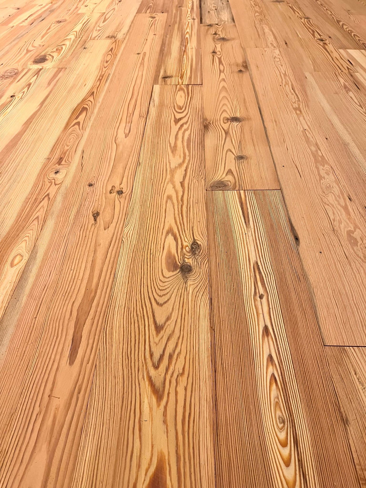 Wooden floorboards with a warm, reddish-brown hue. The grain pattern is prominent, with varying shades and knots.