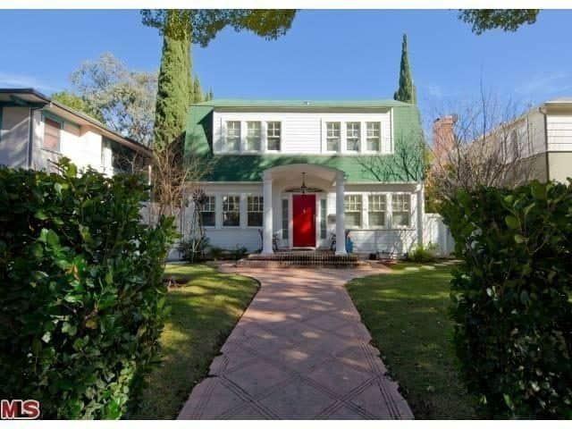 A white house with a green roof has a red door