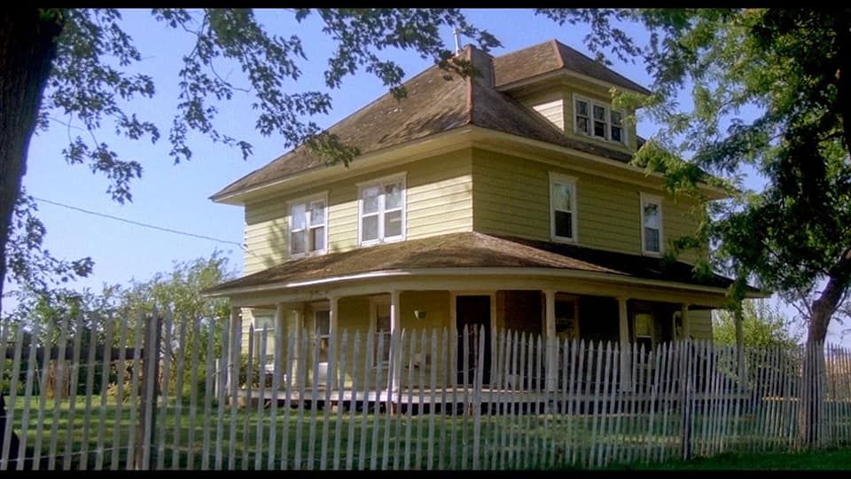 A large yellow house with a white picket fence around it.