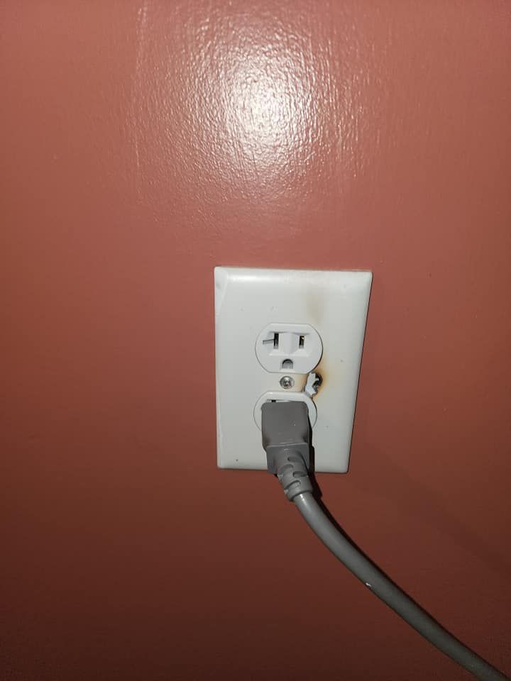A white electrical outlet with a cord plugged into it.