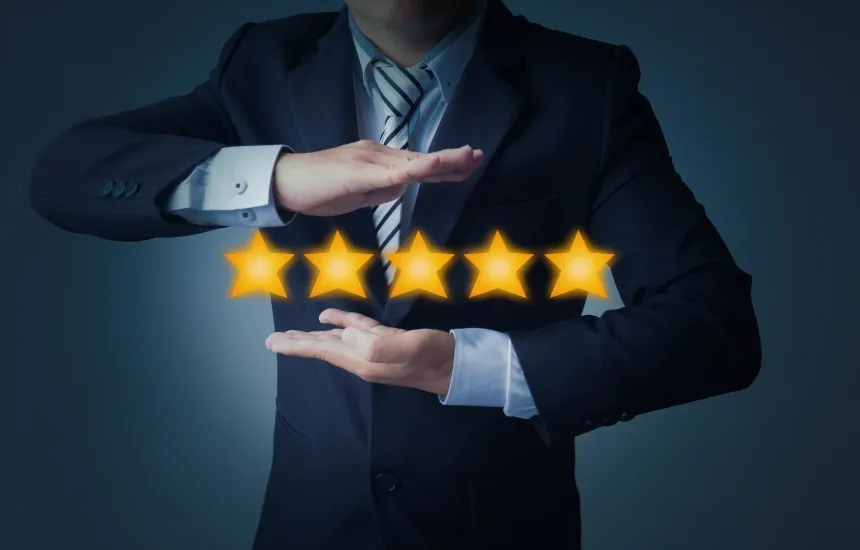 Man in a suit holding his hands open with 5 golden yellow stars in between them.