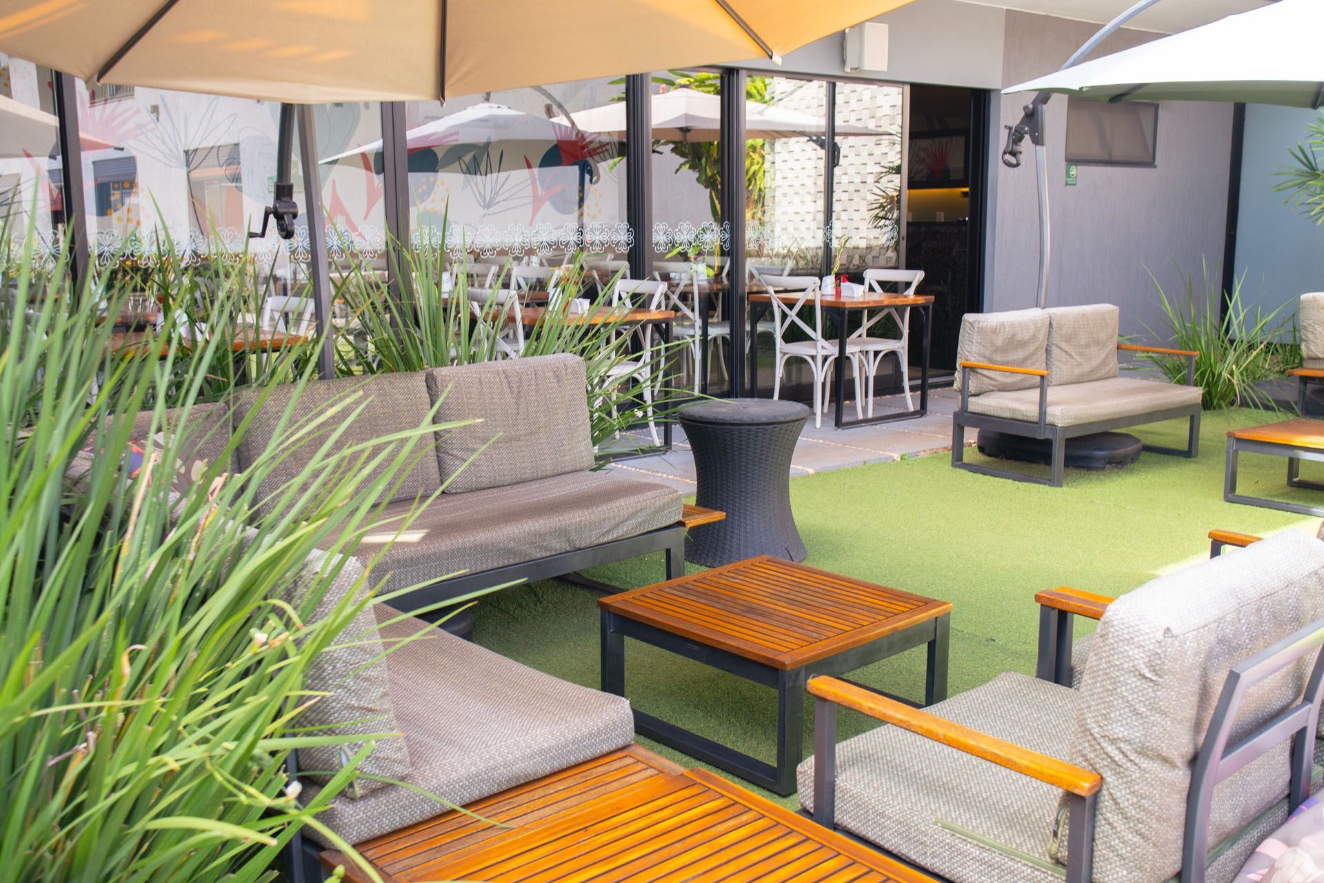 Área externa com sofás, mesas e guarda-sóis.