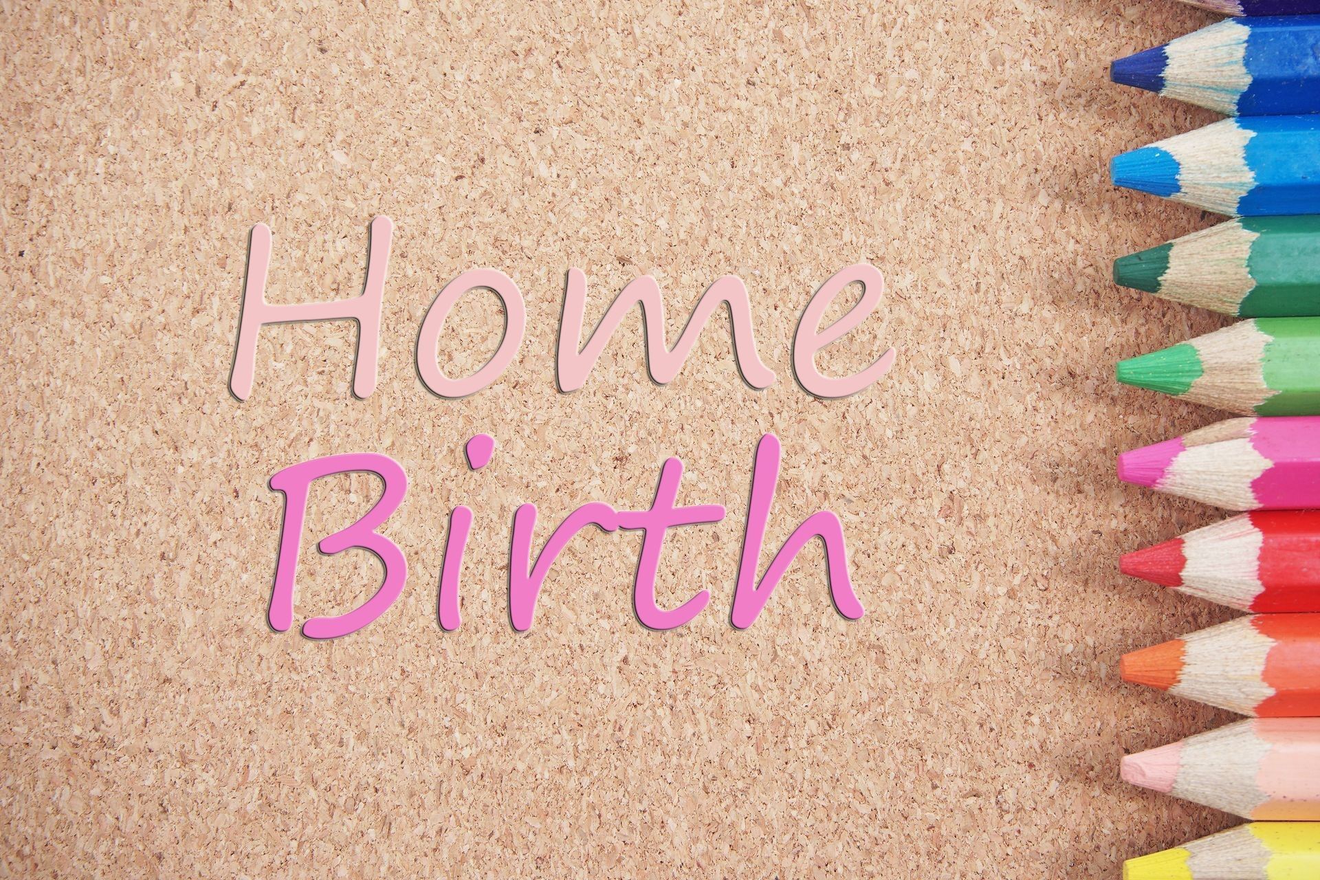 The word home birth is written on a cork board with colored pencils.