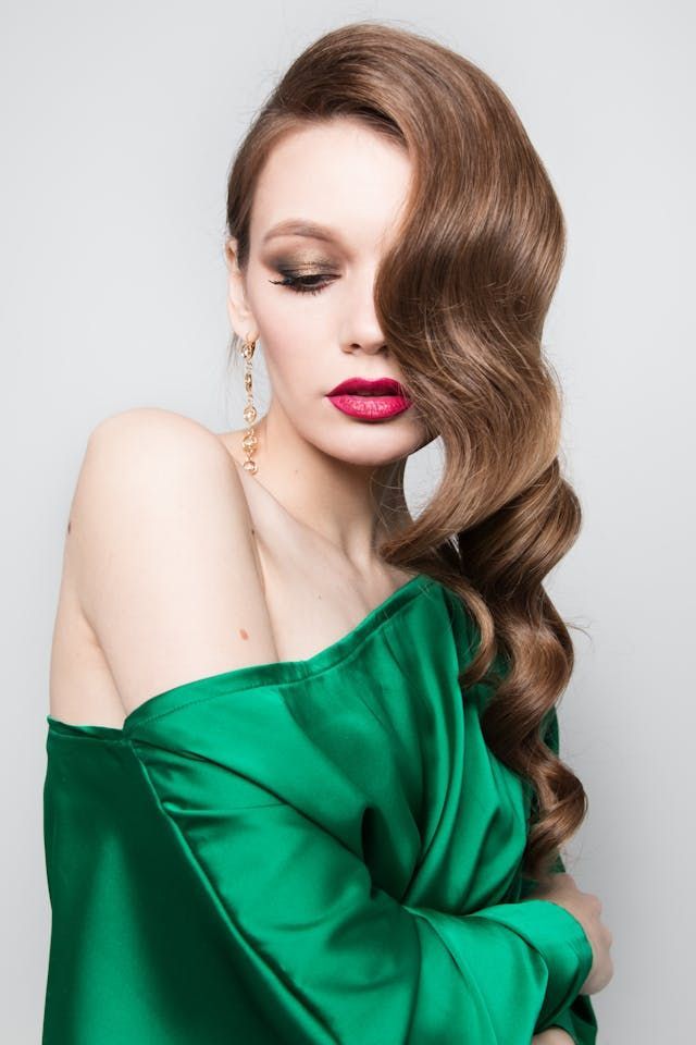 La femme porte une robe verte et du rouge à lèvres rouge.