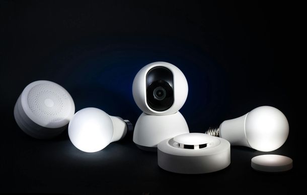Several white smart home cameras and sensors on a dark background
