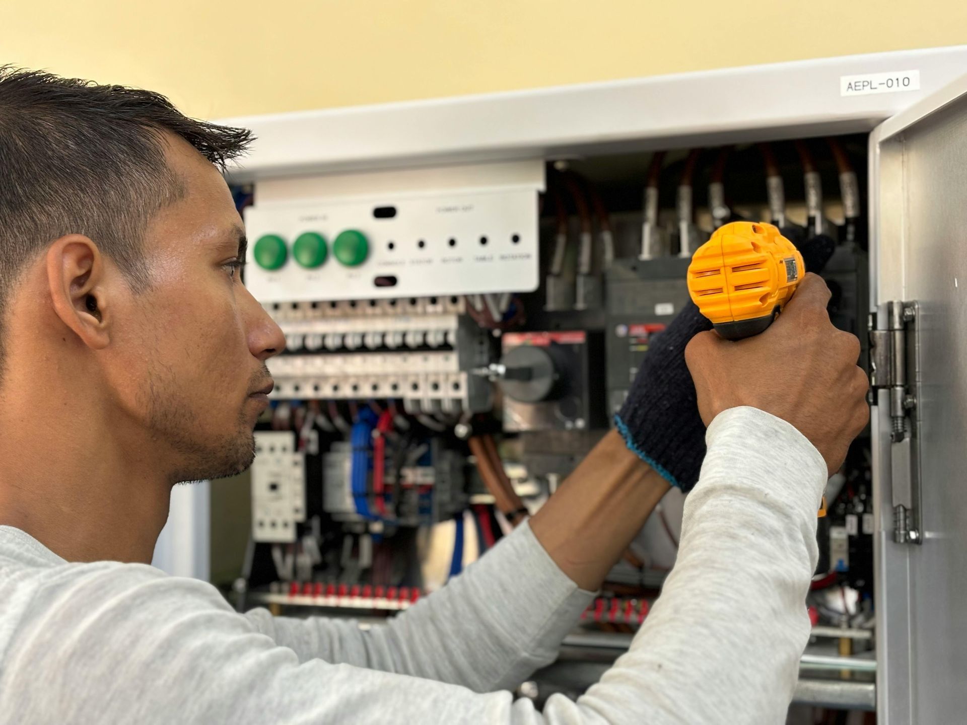 Electrician checking an open electrical panel with a screwdriver and flashlight