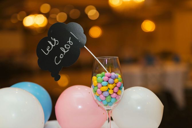 Black cat-shaped sign among pastel balloons and a candy jar at a festive party.