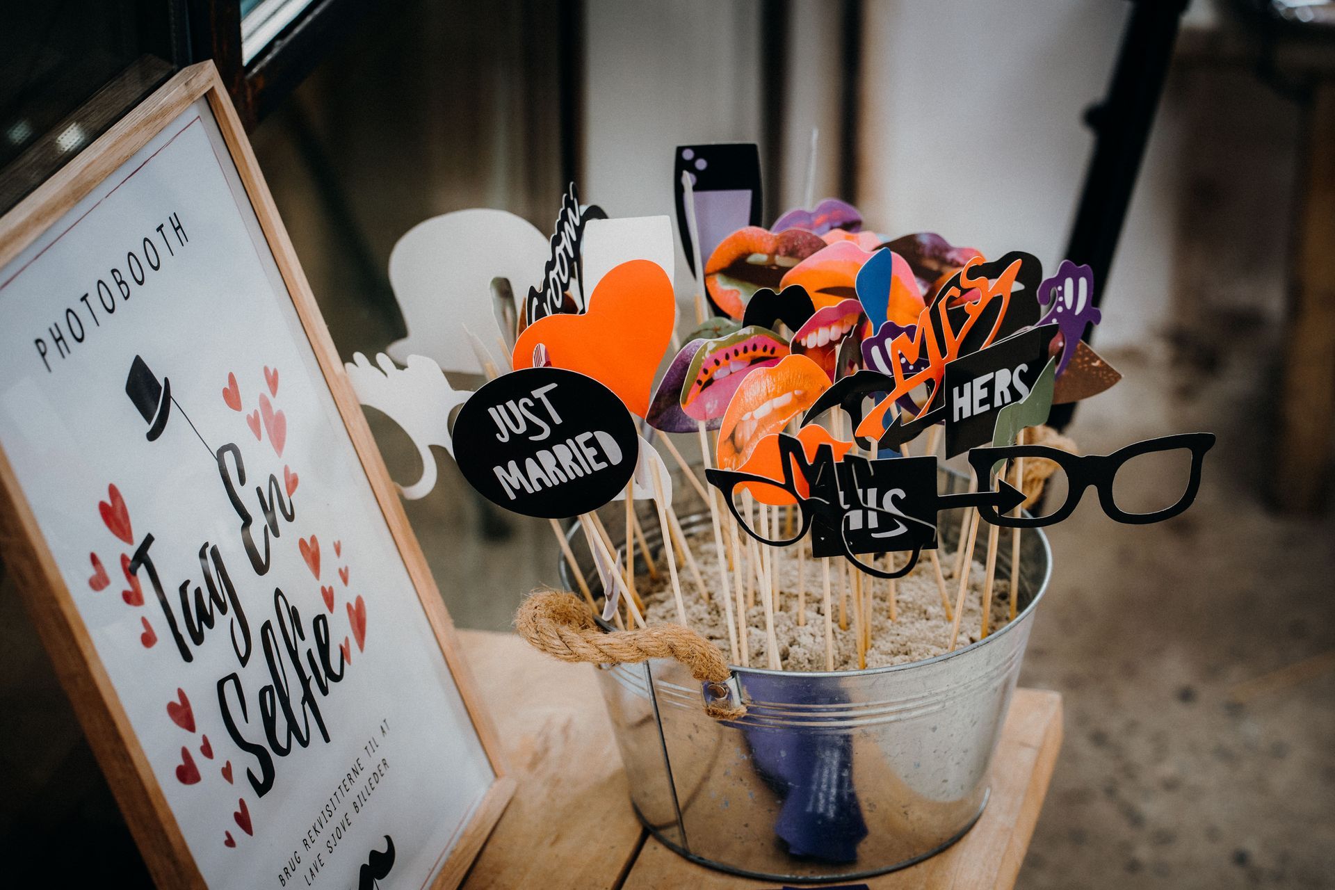 Wedding photo booth props in a basket, including glasses, signs, and a “Just Married” frame.