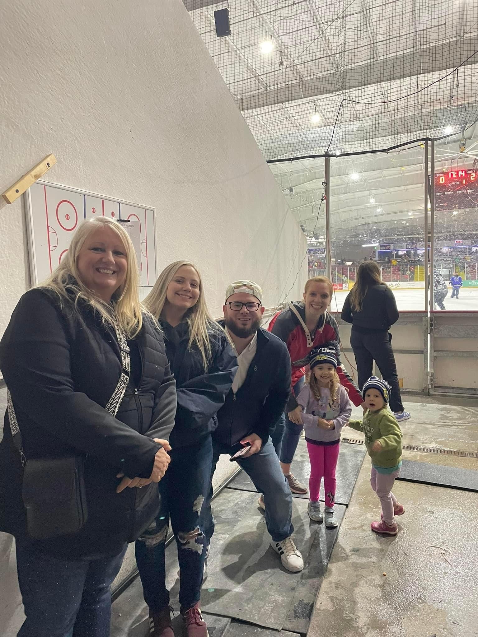 A group of people are standing next to each other in front of an ice rink.