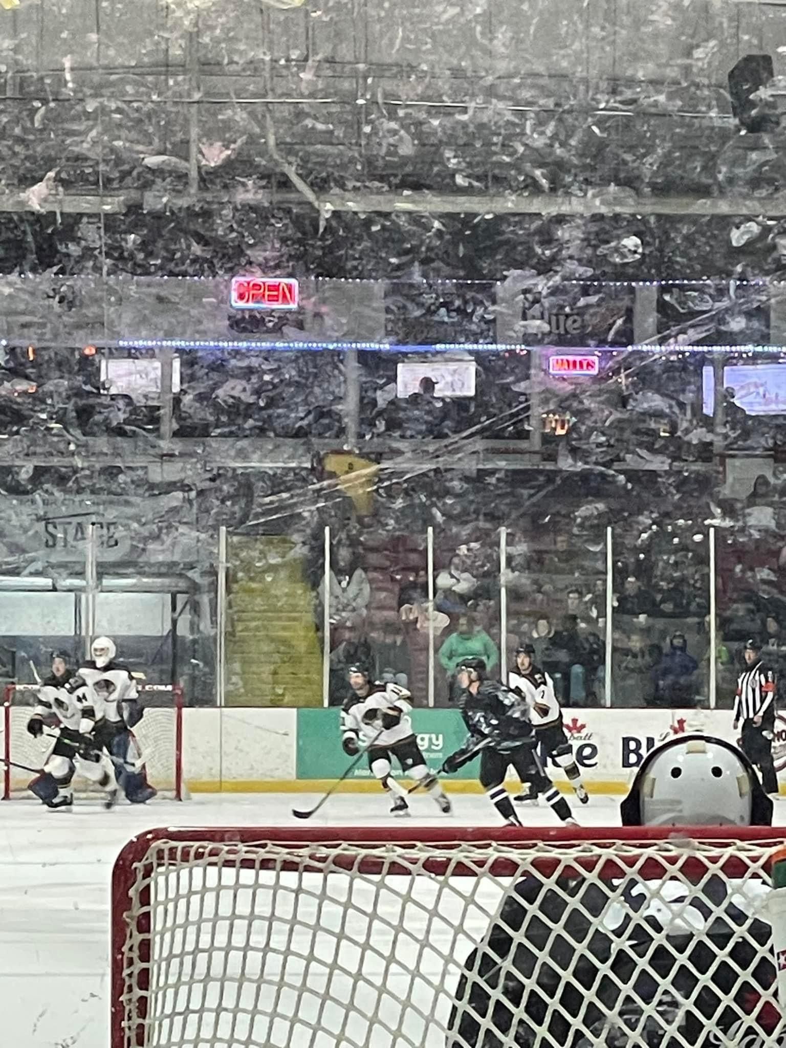 A hockey game is being played in a stadium with a crowd watching.